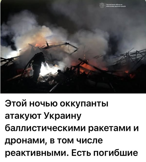 A firefighter working at night near damaged buildings.