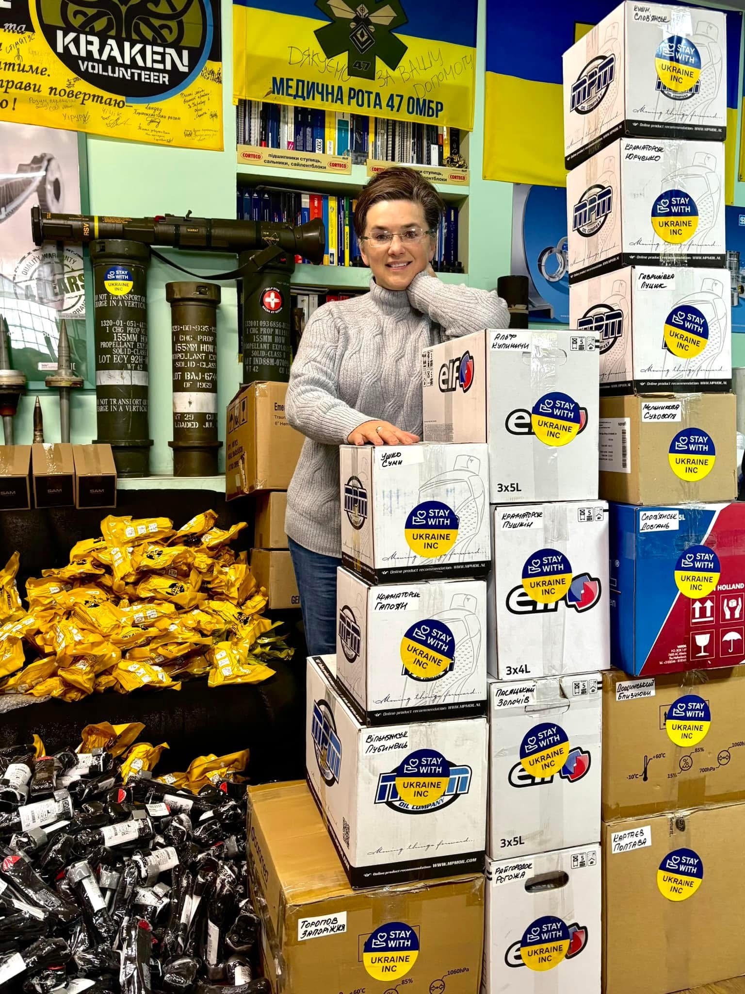 A woman standing with StayWithUkraine Inc. aid boxes.